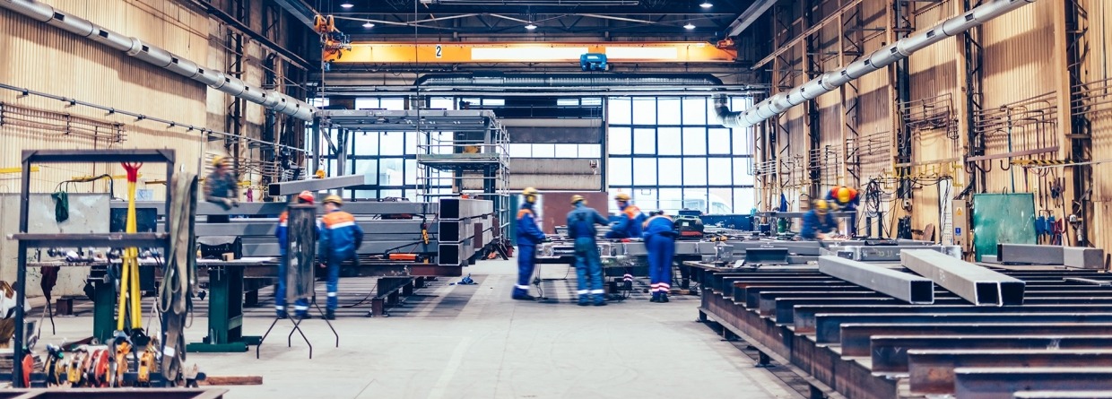 Grote fabriekshal met machines en werkende mensen in blauwe overalls