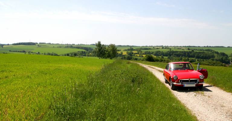 Een rode oldtimer onderweg door de heuvels